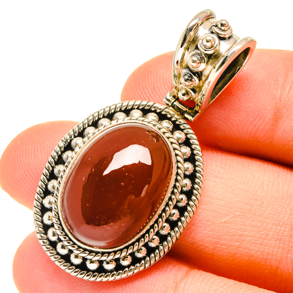 Red onyx pendant in sterling silver with ornate border and gold-tone bail, oval