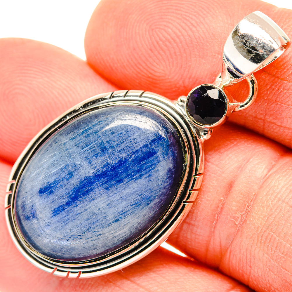 Oval blue stone pendant in sterling silver bezel with two dark purple side gems