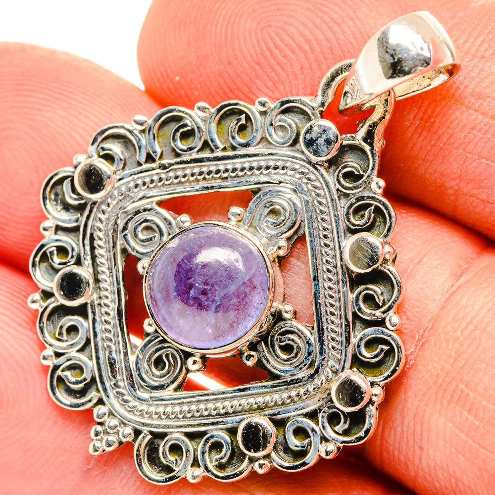 Tanzanite pendant bail at top; round purple center stone with silver filigree border