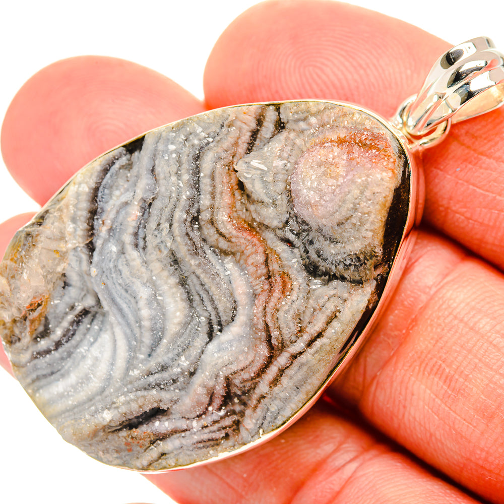 Desert druzy pendant close-up; gray geode texture with glittering pink center, silver bail