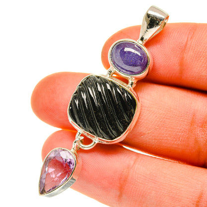 Sterling silver pendant held in hand with purple round stone, black oval stone, and pink teardrops