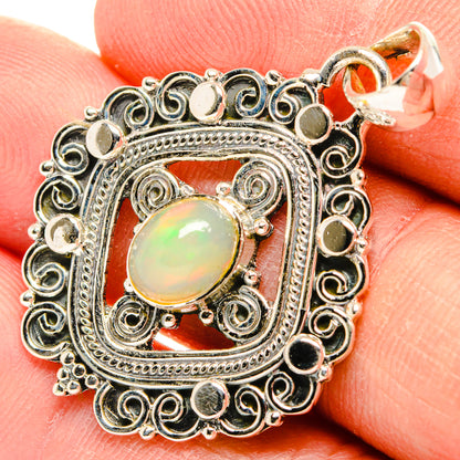 Sterling silver oval opal pendant close-up on fingertip, ornate filigree frame