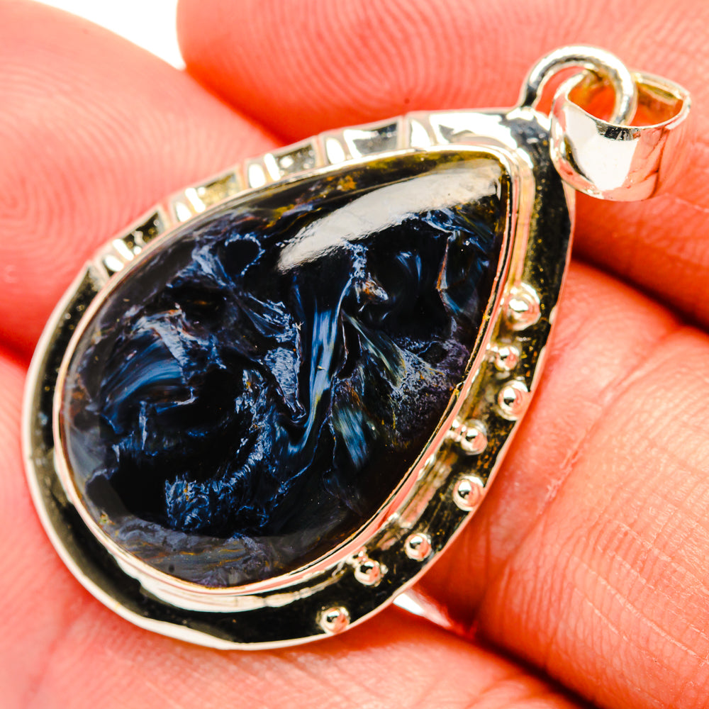 Close-up sterling silver pietersite teardrop pendant with faceted blue stone bezel