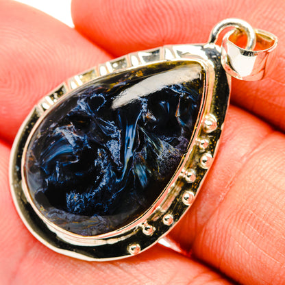 Close-up sterling silver pietersite teardrop pendant with faceted blue stone bezel