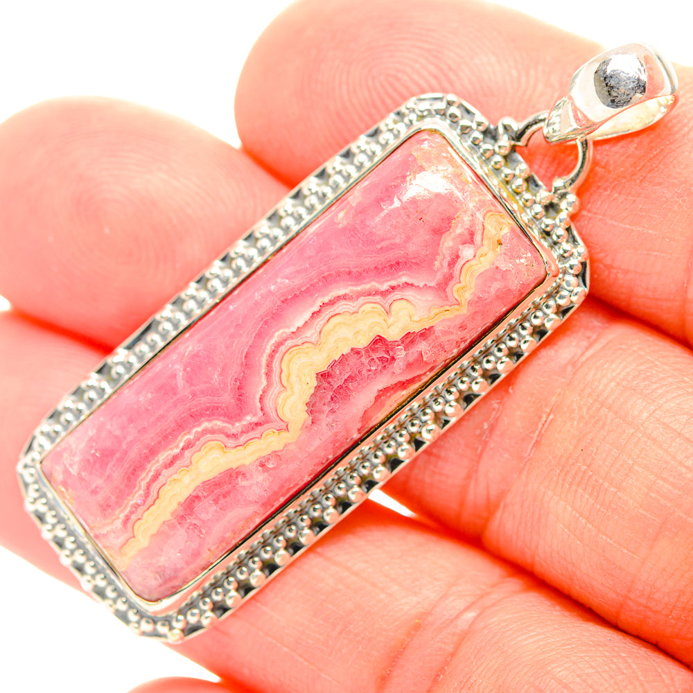 Rectangular rhodochrosite pendant close-up, pink with yellow bands, silver bezel and bail
