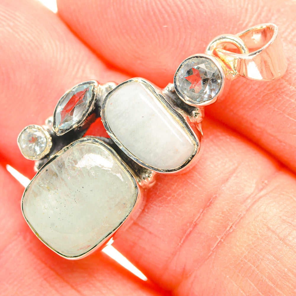 Sterling silver pendant close-up with two oval opalescent stones and round blue topaz