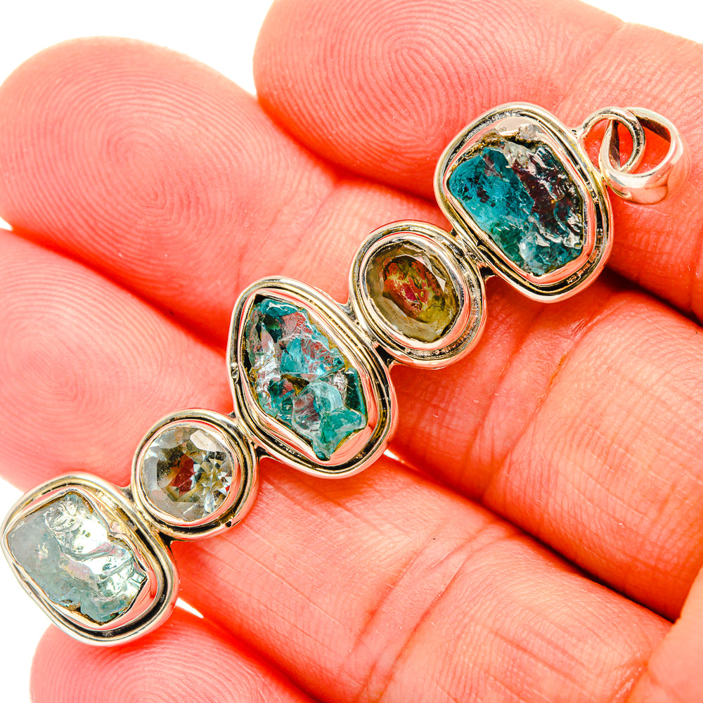 Close-up of oval rough apatite pendants with blue-green stones in silver bezel links