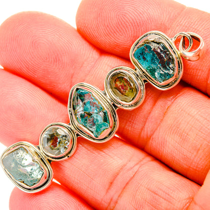 Close-up of oval rough apatite pendants with blue-green stones in silver bezel links