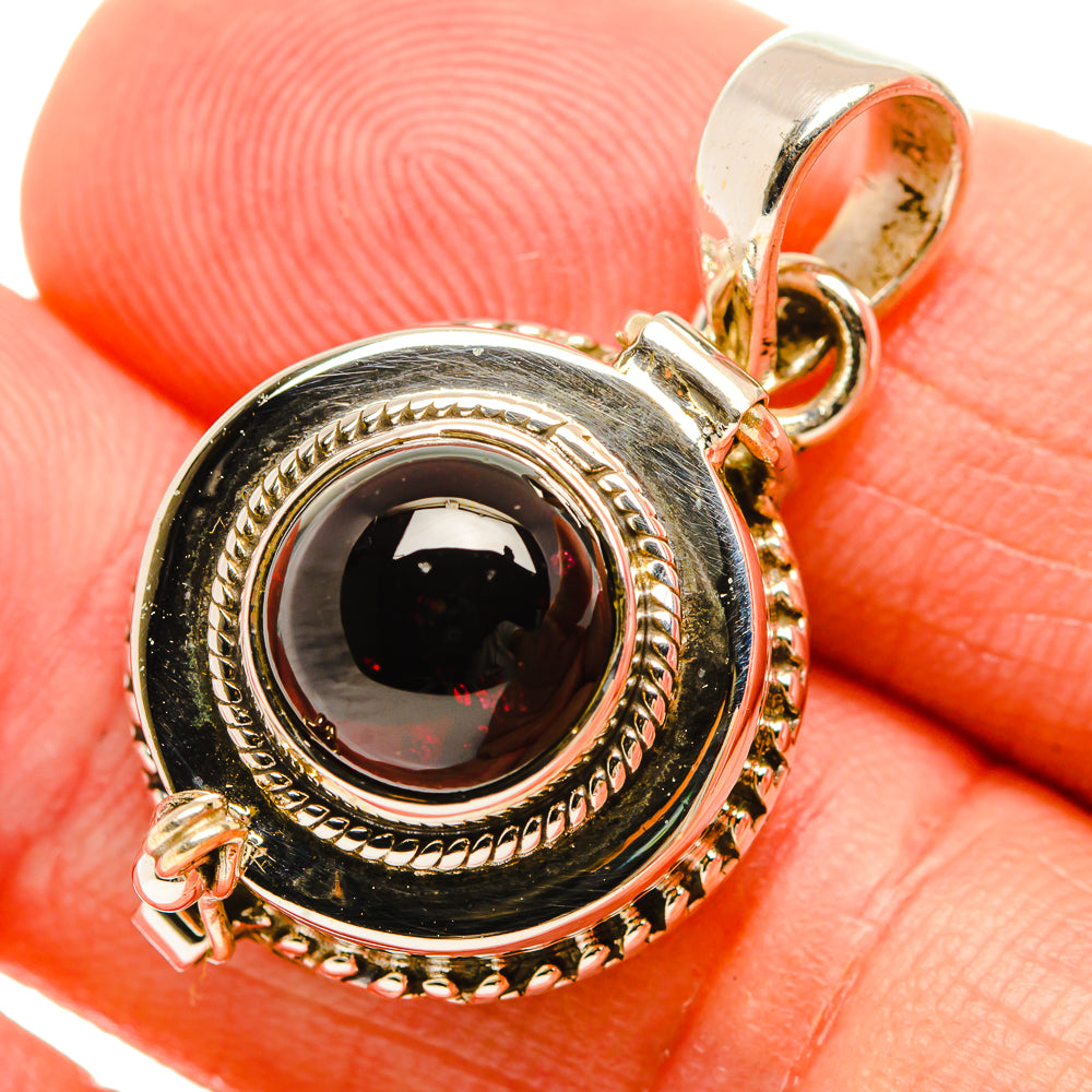 Sterling silver pendant close-up with oval dark gemstone in rope-edged bezel