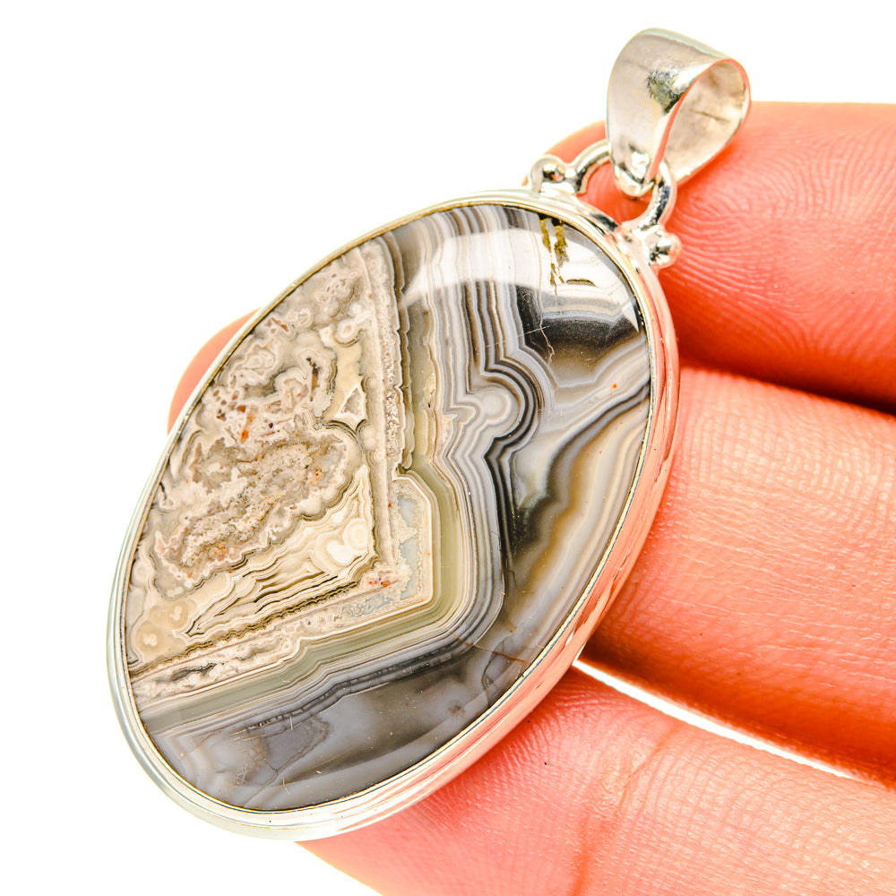 Oval lace agate pendant with sterling silver bezel, close-up on hand, multi-color bands.