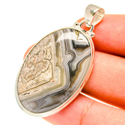 Oval lace agate pendant with sterling silver bezel, close-up on hand, multi-color bands.