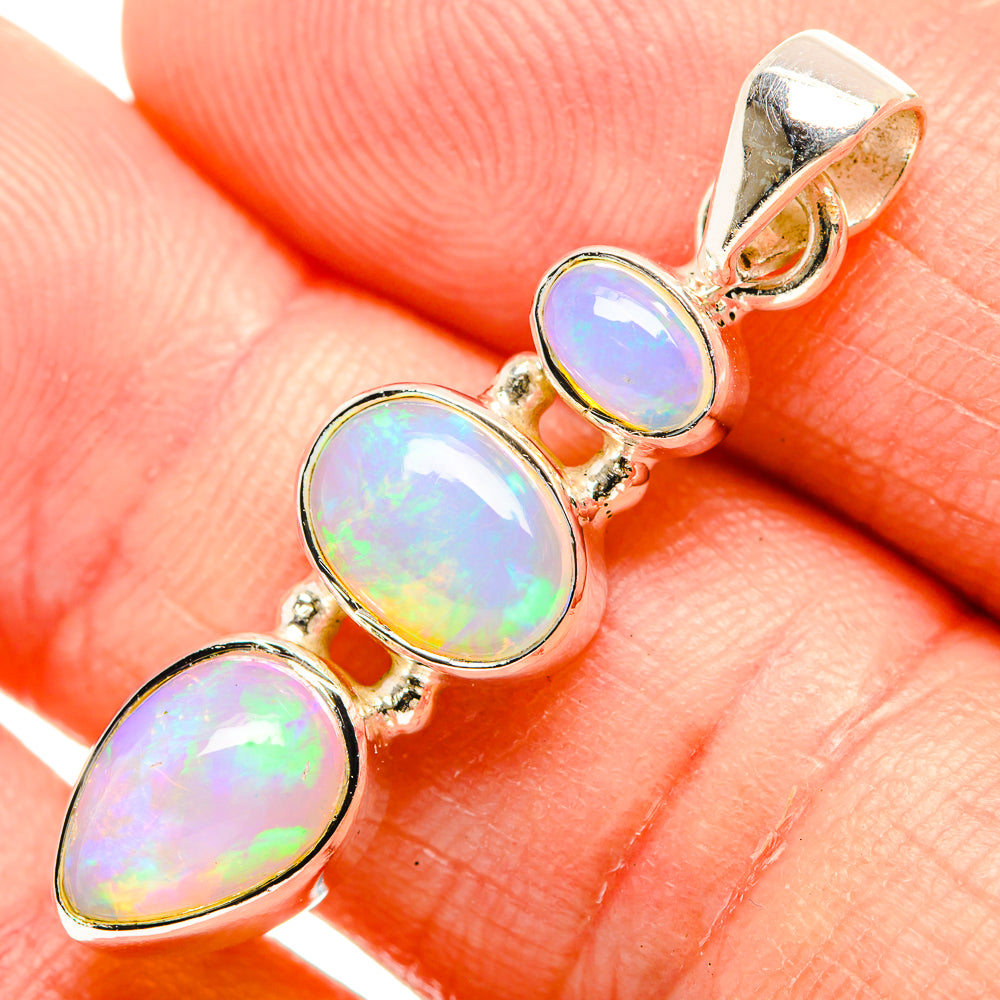 Close-up opal pendant with three oval opal stones in silver and gold-tone prong settings