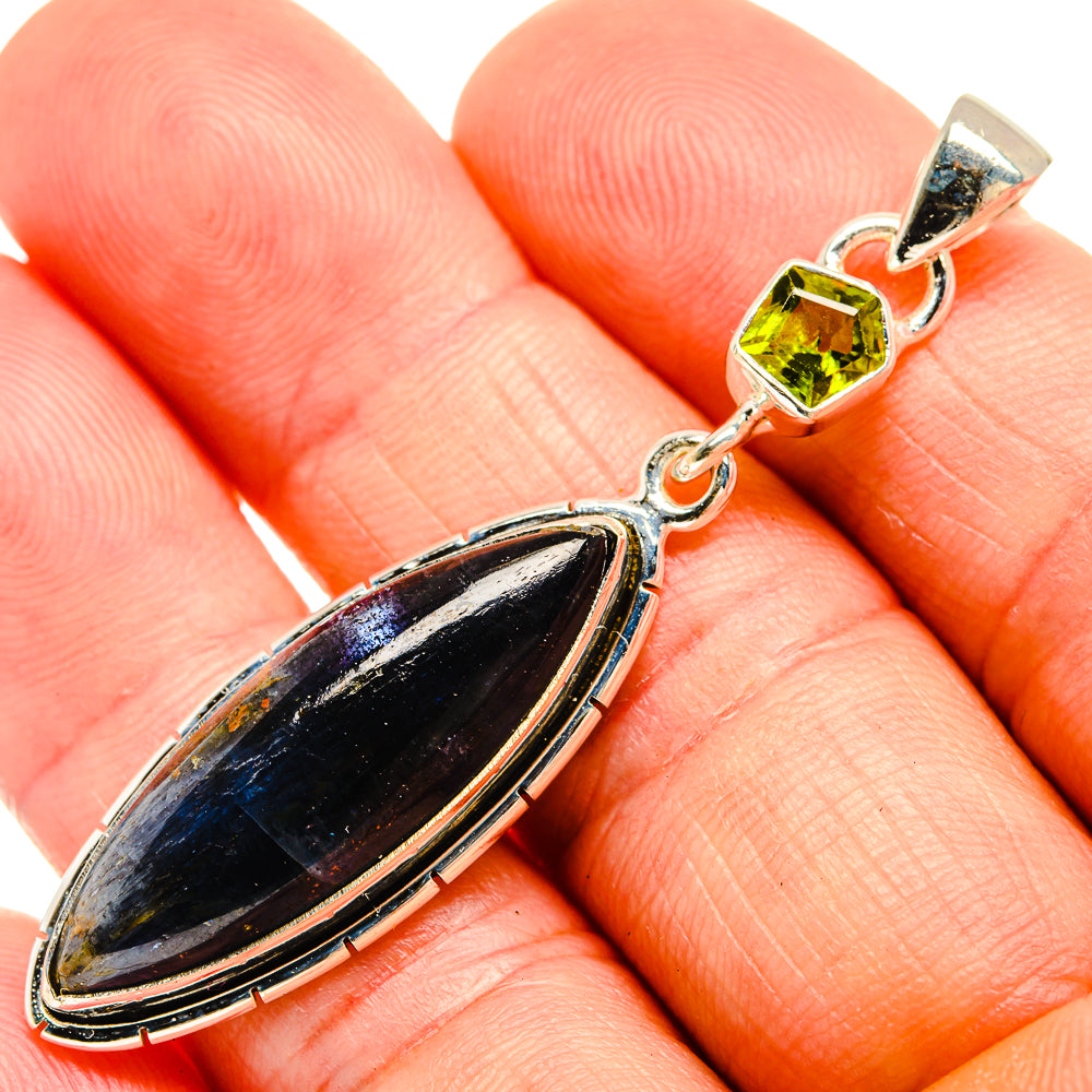 Close-up sterling silver pendant showing dark blue oval stone and green peridot bail