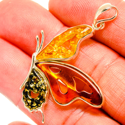 Butterfly pendant closeup with red and amber wings and ornate sterling silver details