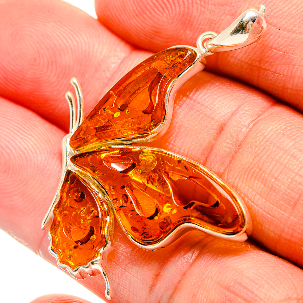 Amber butterfly pendant close-up in sterling-silver setting with orange translucent wings
