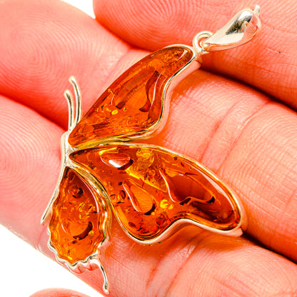 Amber butterfly pendant close-up in sterling-silver setting with orange translucent wings