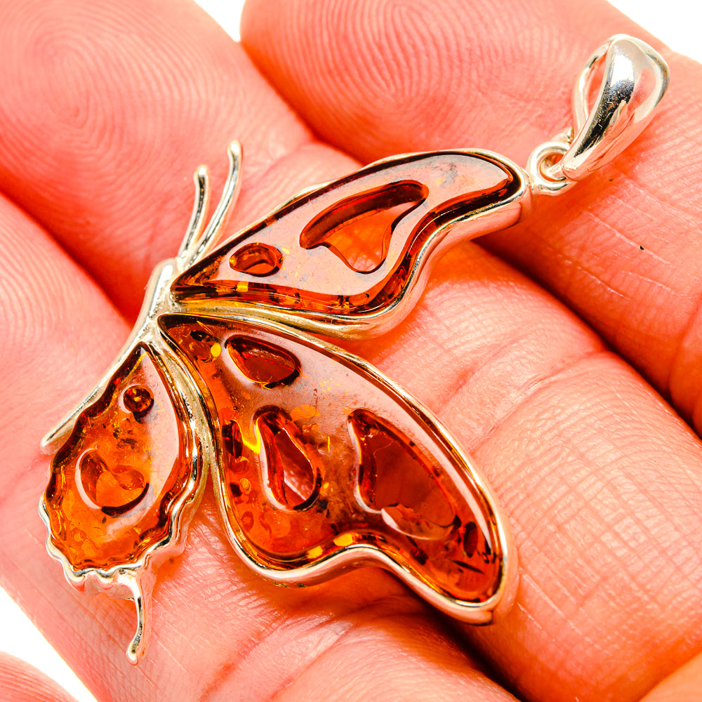 Close-up of orange amber butterfly pendant with 925 sterling silver bail and frame