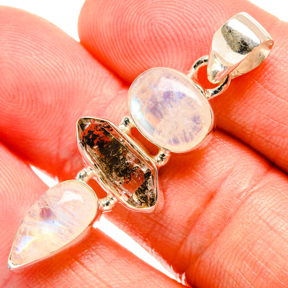 Sterling silver pendant with two round opal moonstone cabochons and one dark irregular stone.