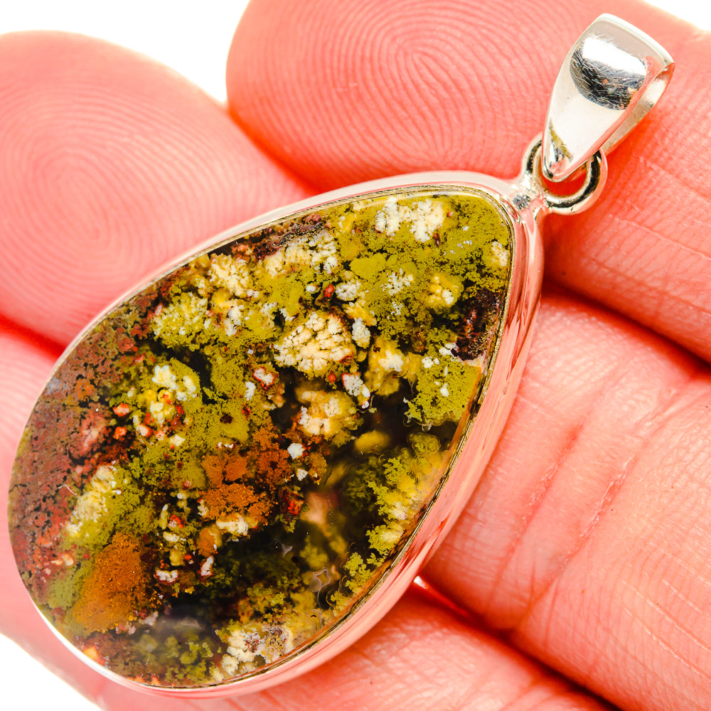 Oval silver pendant with plume agate teardrop stone, mottled green gold brown, close-up.