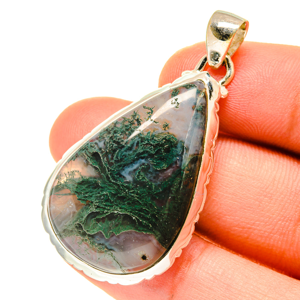 Green moss agate teardrop pendant in sterling silver, close-up on stone surface