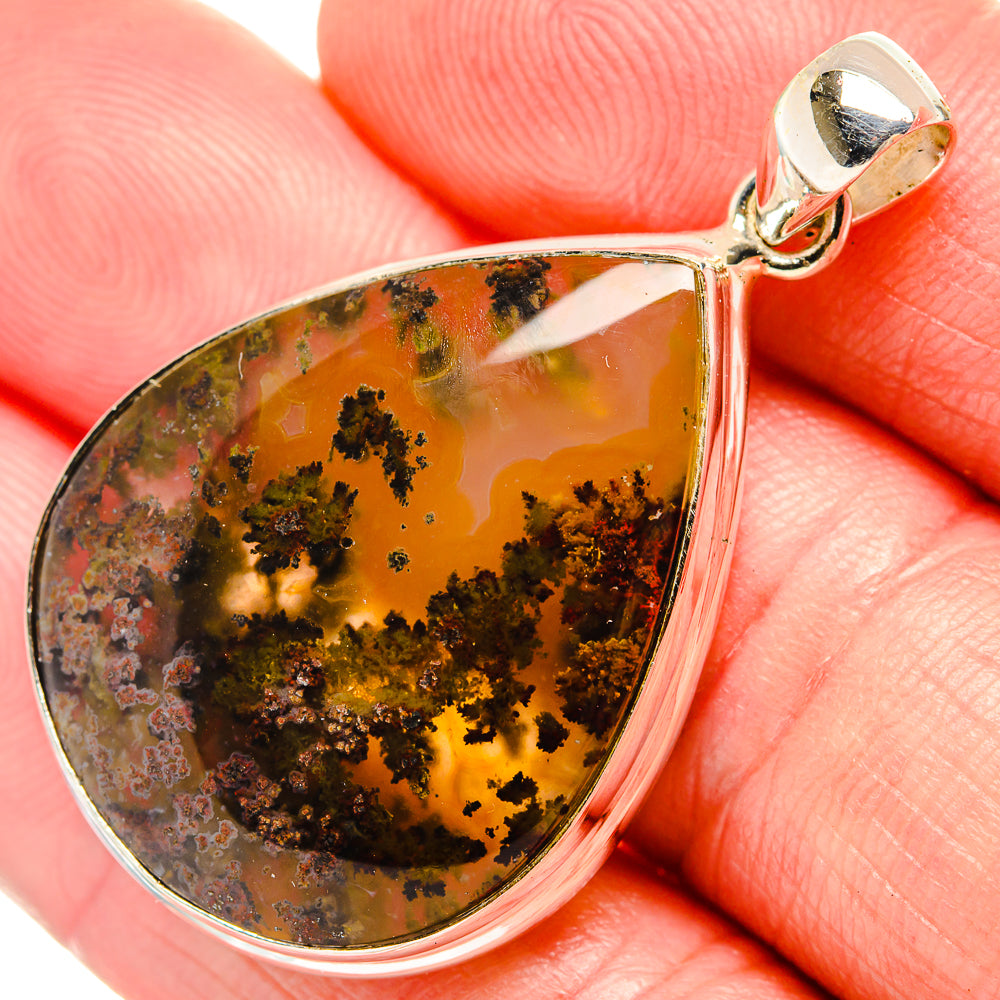 Teardrop plume agate pendant close-up, warm amber with dark inclusions; silver bail