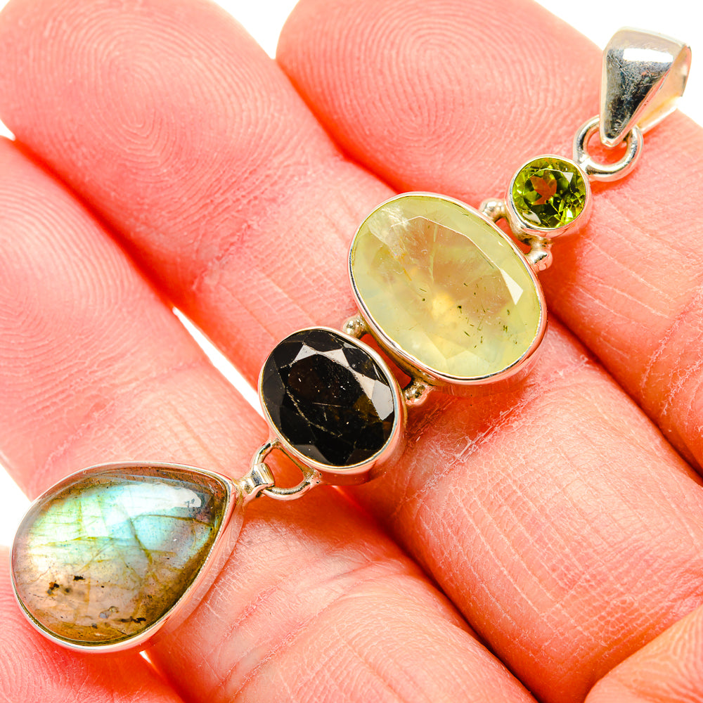 Gemstone pendant close to hand: sterling silver with green round and pale yellow-green teardrops