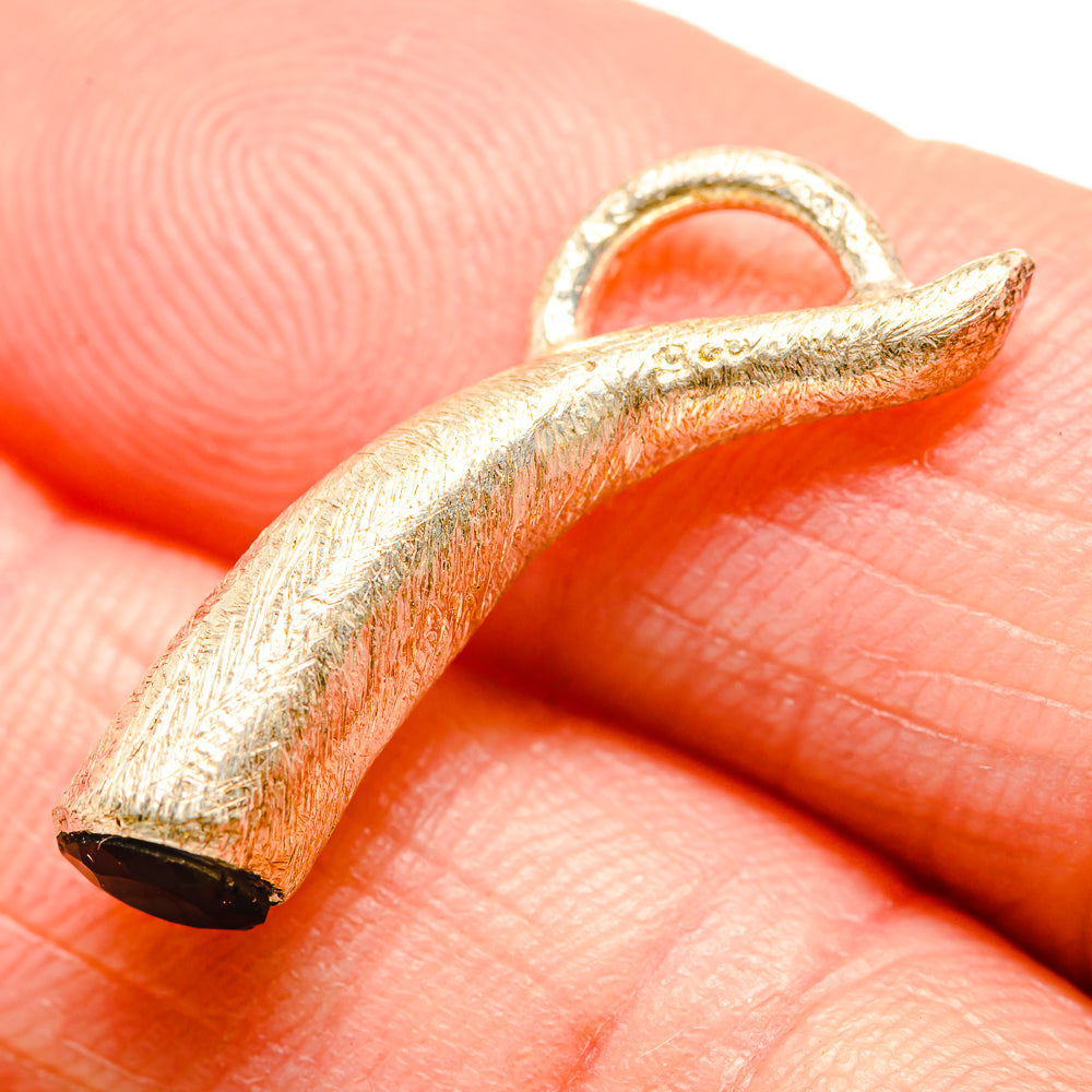 Leaf-shaped pendant with textured silver frame and dark black stone, close-up view