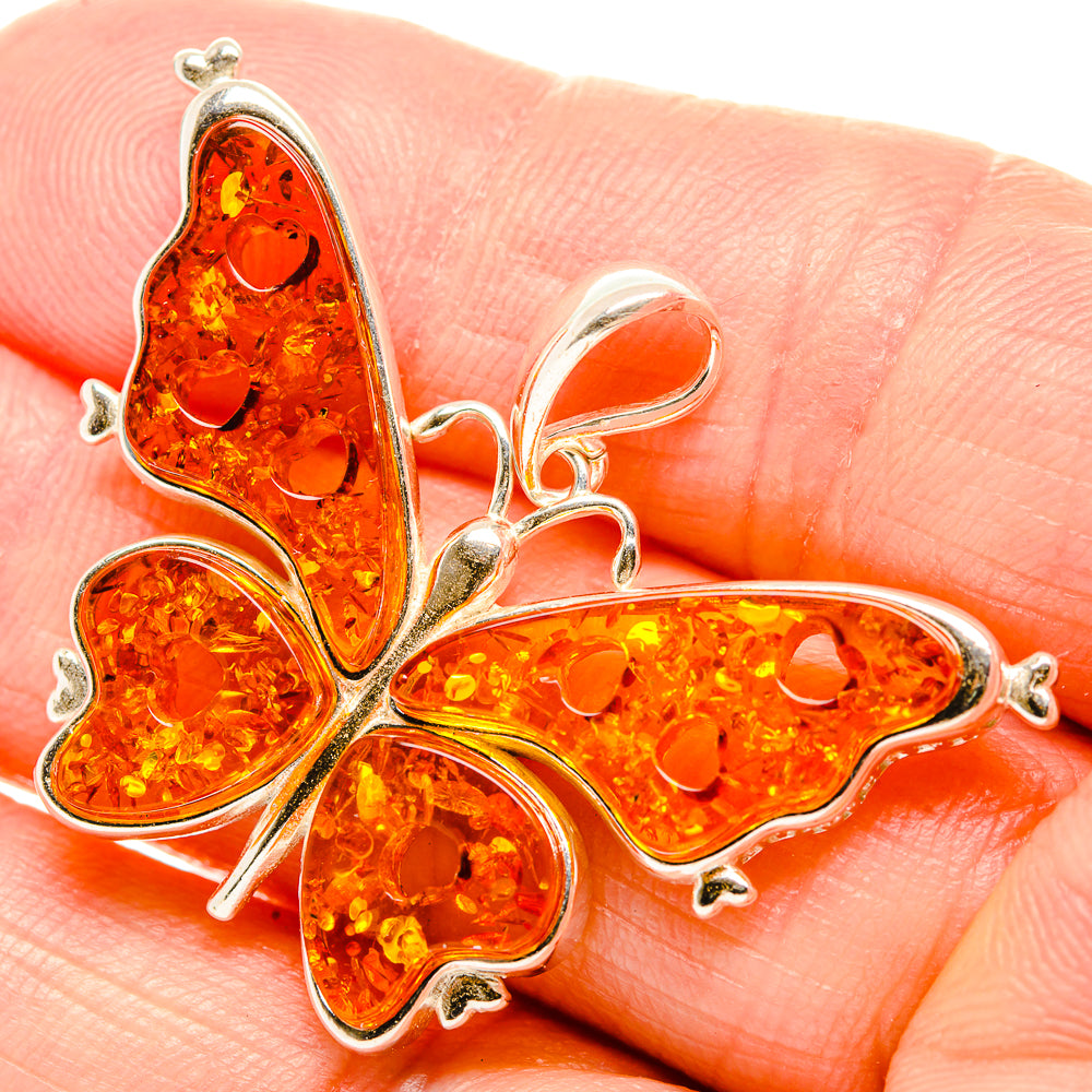 Orange amber butterfly pendant with 925 sterling silver frame, close-up on amber body