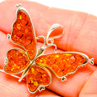 Orange amber butterfly pendant with 925 sterling silver frame, close-up on amber body