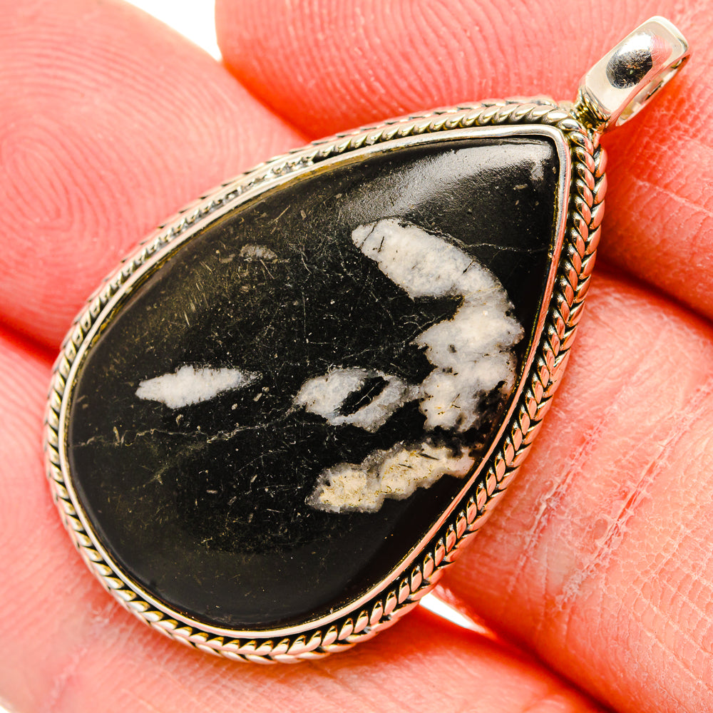 Close-up teardrop black stone pendant with white veining, twisted rope bezel