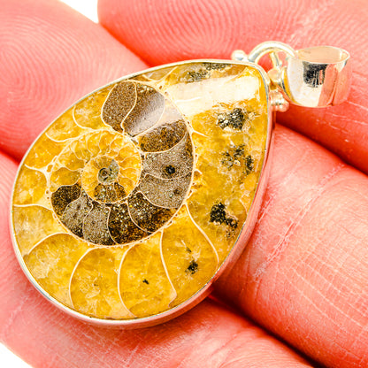 Fossil ammolite teardrop pendant with yellow-orange stone, dark fossil inclusions, silver loop