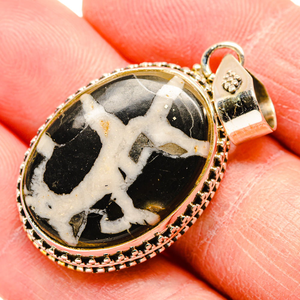 Oval geode pendant in silver bezel with black-and-cream stone, bail and top cap