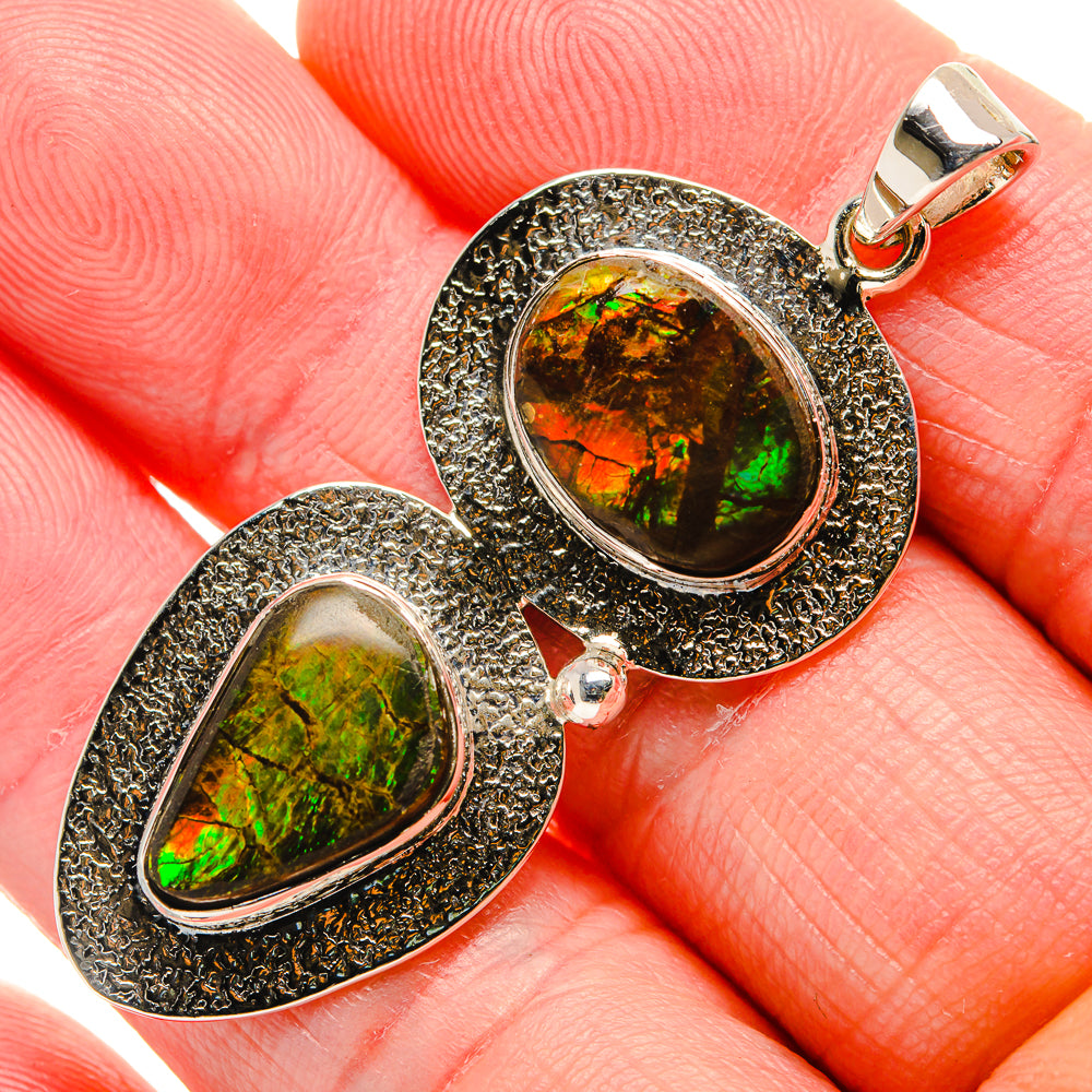 Sterling silver ammolite pendant with oval rainbow stone and textured frame, loop bail