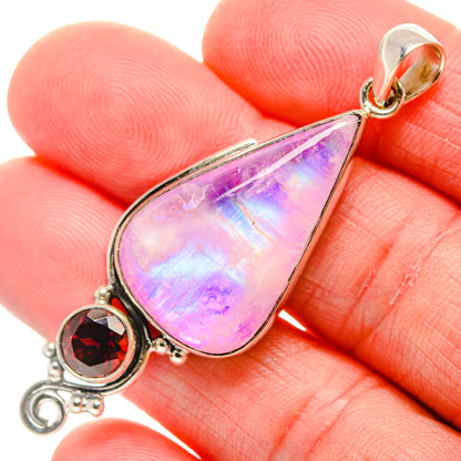 Close-up teardrop moonstone pendant with round red garnet stone in silver setting