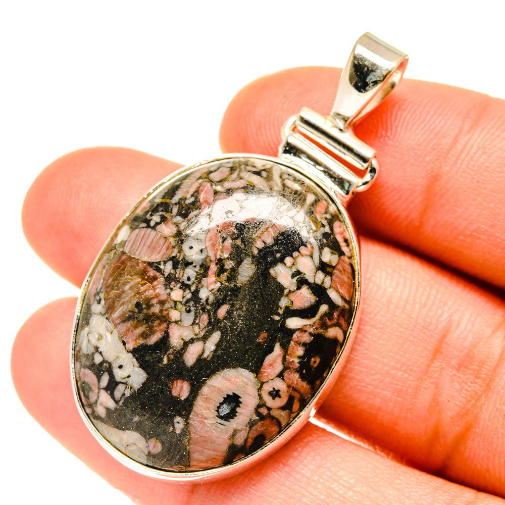 Oval sterling silver fossil pendant with speckled black, pink, and white cabochon stone.
