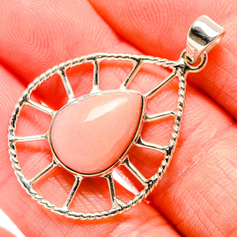 Oval pink opal cabochon pendant in silver openwork frame with bail