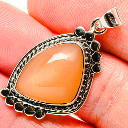 Peach moonstone pendant close-up: teardrop stone with black bead border in silver