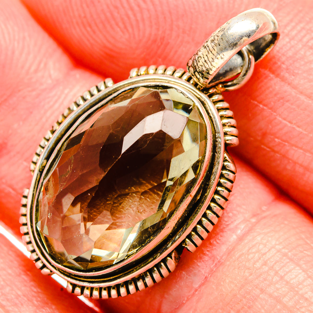 Oval faceted gemstone pendant with sterling silver setting and top loop, green-gold hue