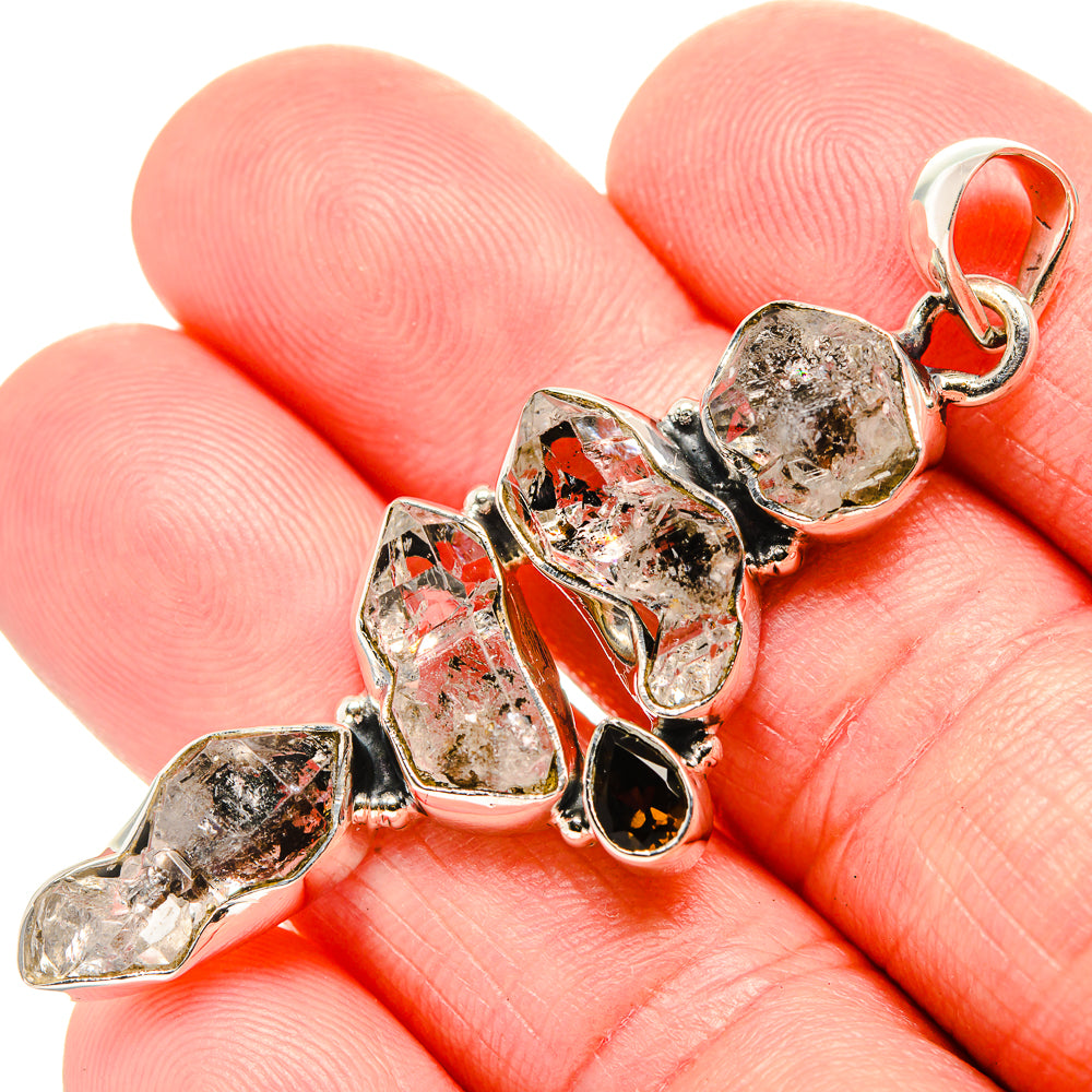Sterling silver pendant viewed on hand, with faceted clear and dark red stones