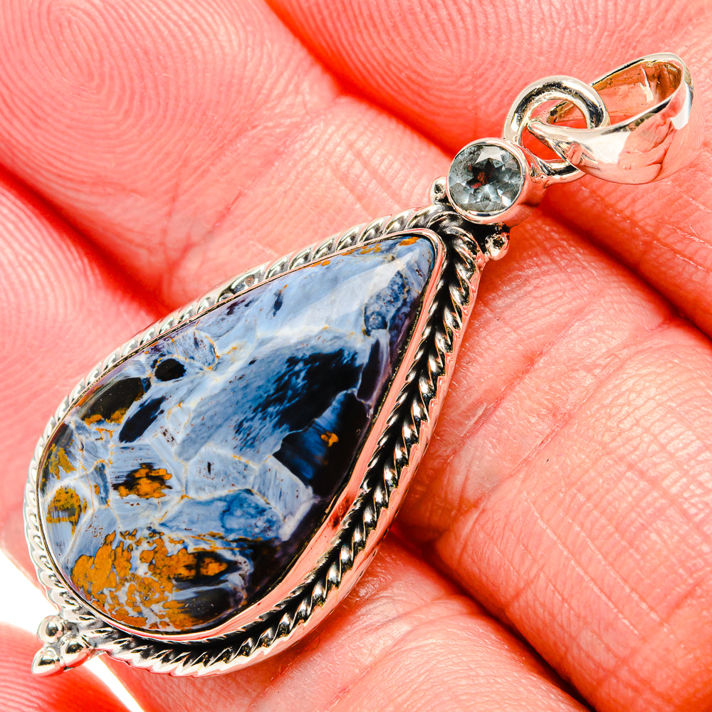 Closeup of pietersite teardrop pendant with round blue topaz accents, 925 sterling silver