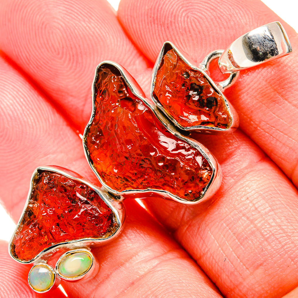 Rough red garnet pendant with sterling silver prongs and two round green opal accents