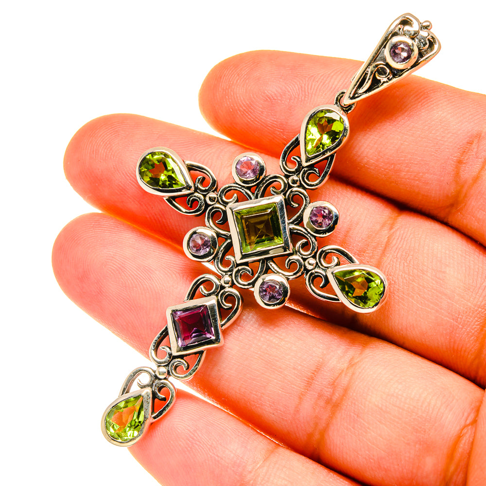 Cross pendant in silver-tone with green, purple, and pink gemstone accents, ornate filigree.