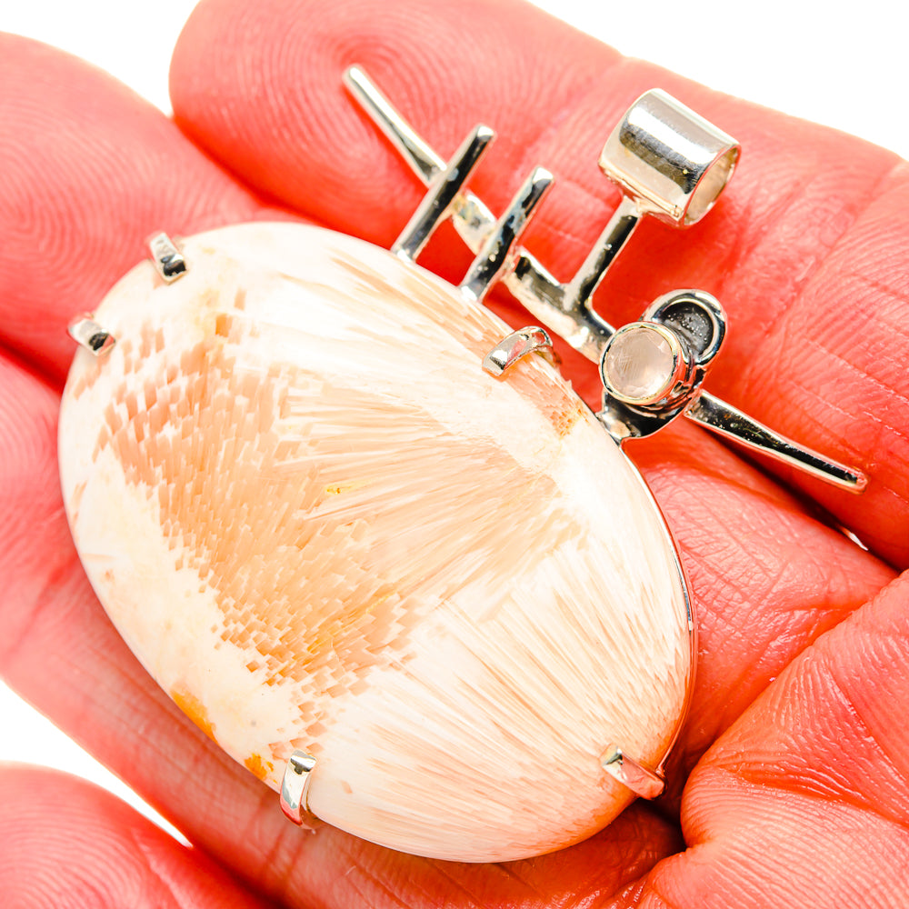 Scolecite pendant close-up: oval peach cabochon with silver prongs and round bezel accents