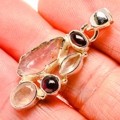 Close-up sterling silver pendant with rough pink stone, oval pink cabochon, and red round gem