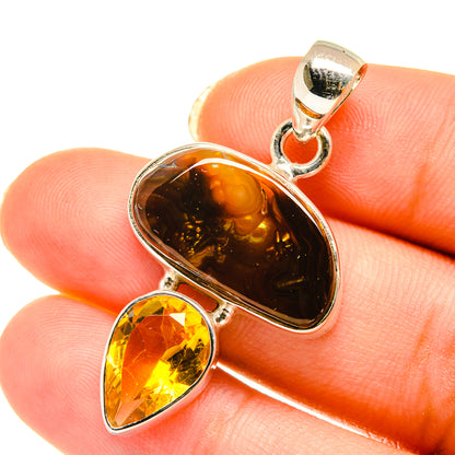 Fire agate and citrine pendant with polished silver bail, held on fingertip