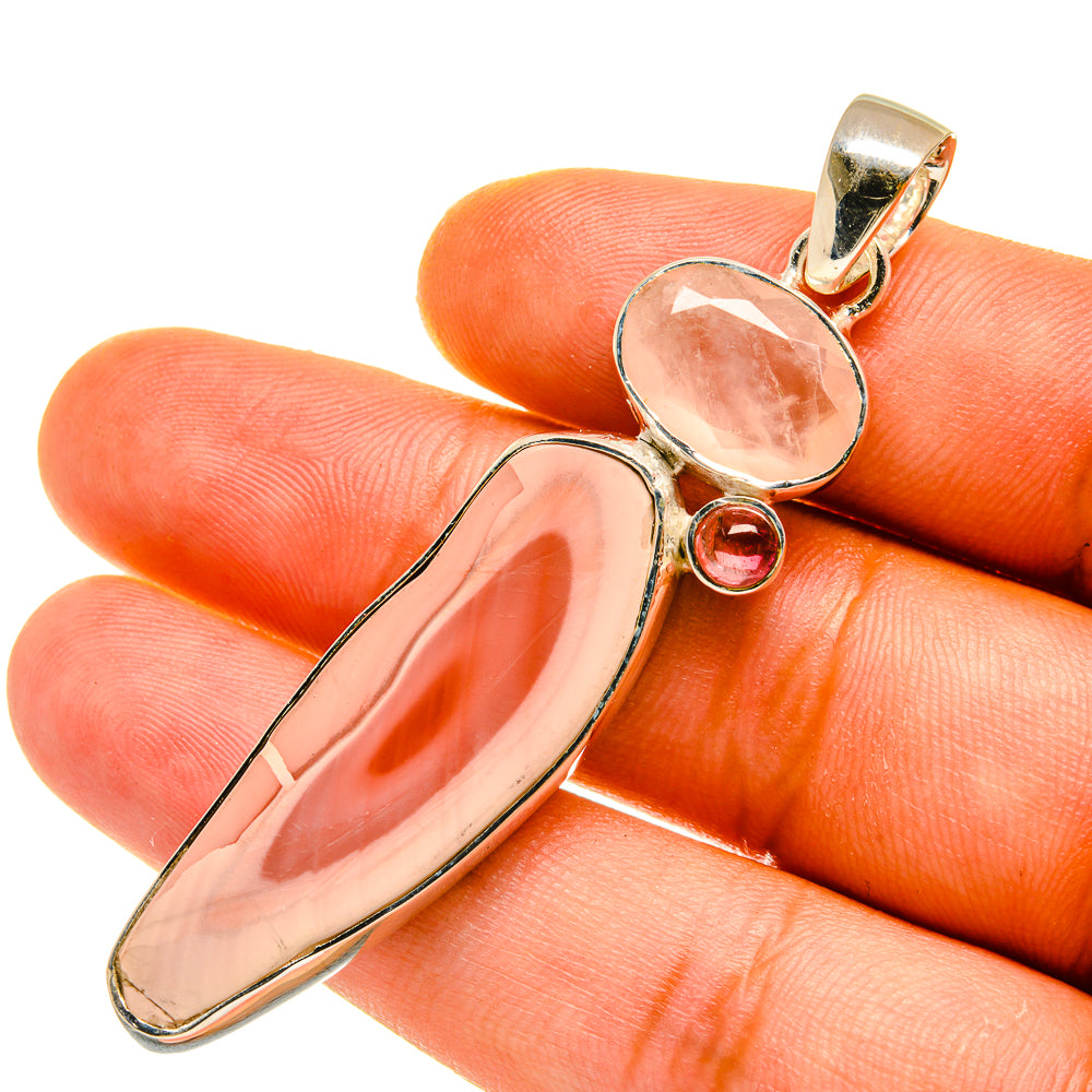 Gold-tone gemstone pendant close-up: oval peach-pink stone with small round pink gem