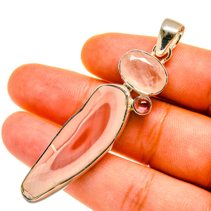 Gold-tone gemstone pendant close-up: oval peach-pink stone with small round pink gem