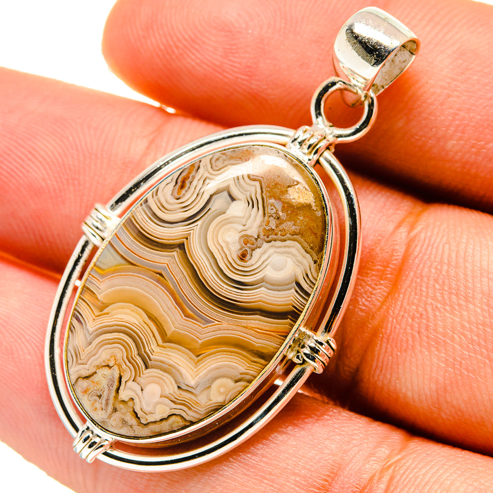 Oval lace agate pendant in 925 sterling silver with gold-toned banded stone, on finger