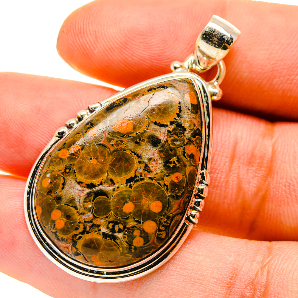 Teardrop jasper pendant close-up, orange mottled stone with silver rim and gold bail