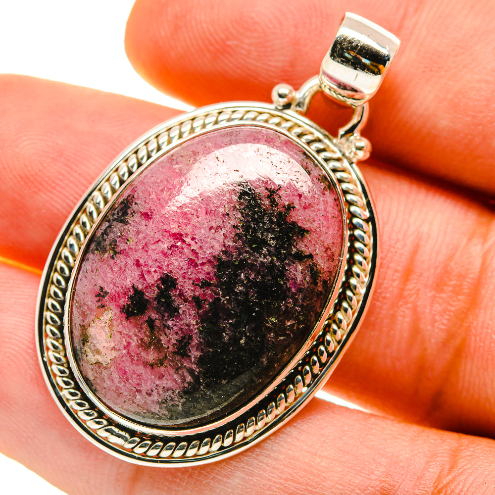 Rhodonite oval pendant in 925 sterling silver on finger, black and pink speckled gemstone